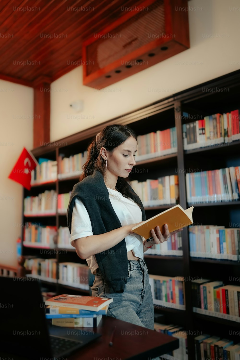 uma mulher lendo um livro em uma biblioteca