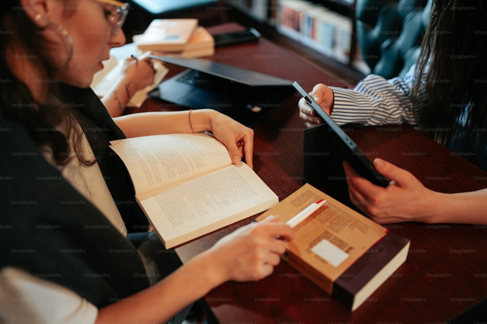 two women are sitting at a table with books