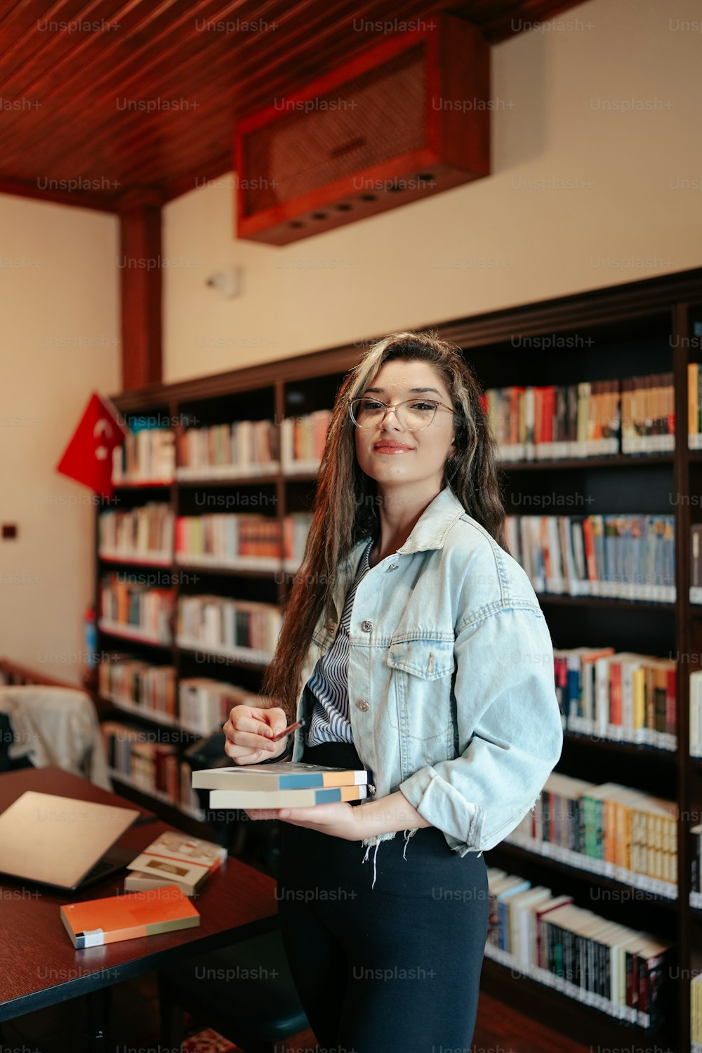 a woman standing in front of a bookshelf holding a book