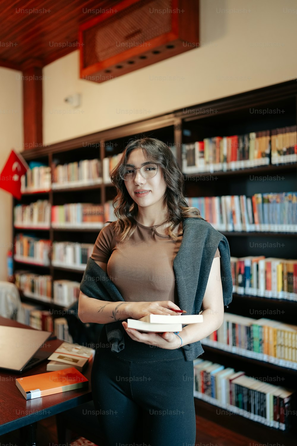 a woman standing in a library holding a book