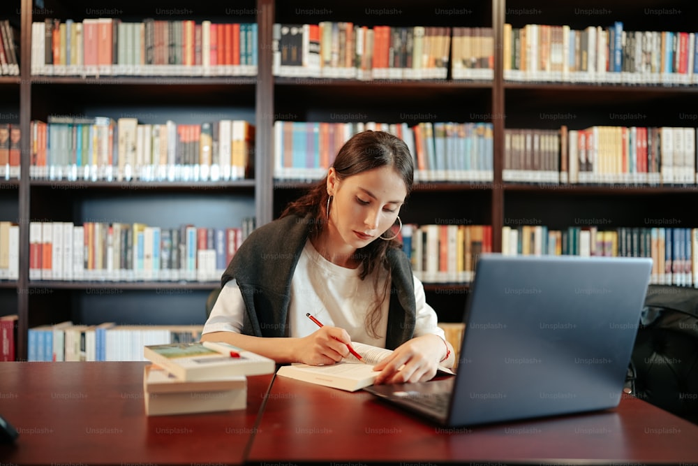 a woman sitting at a table in front of a laptop computer