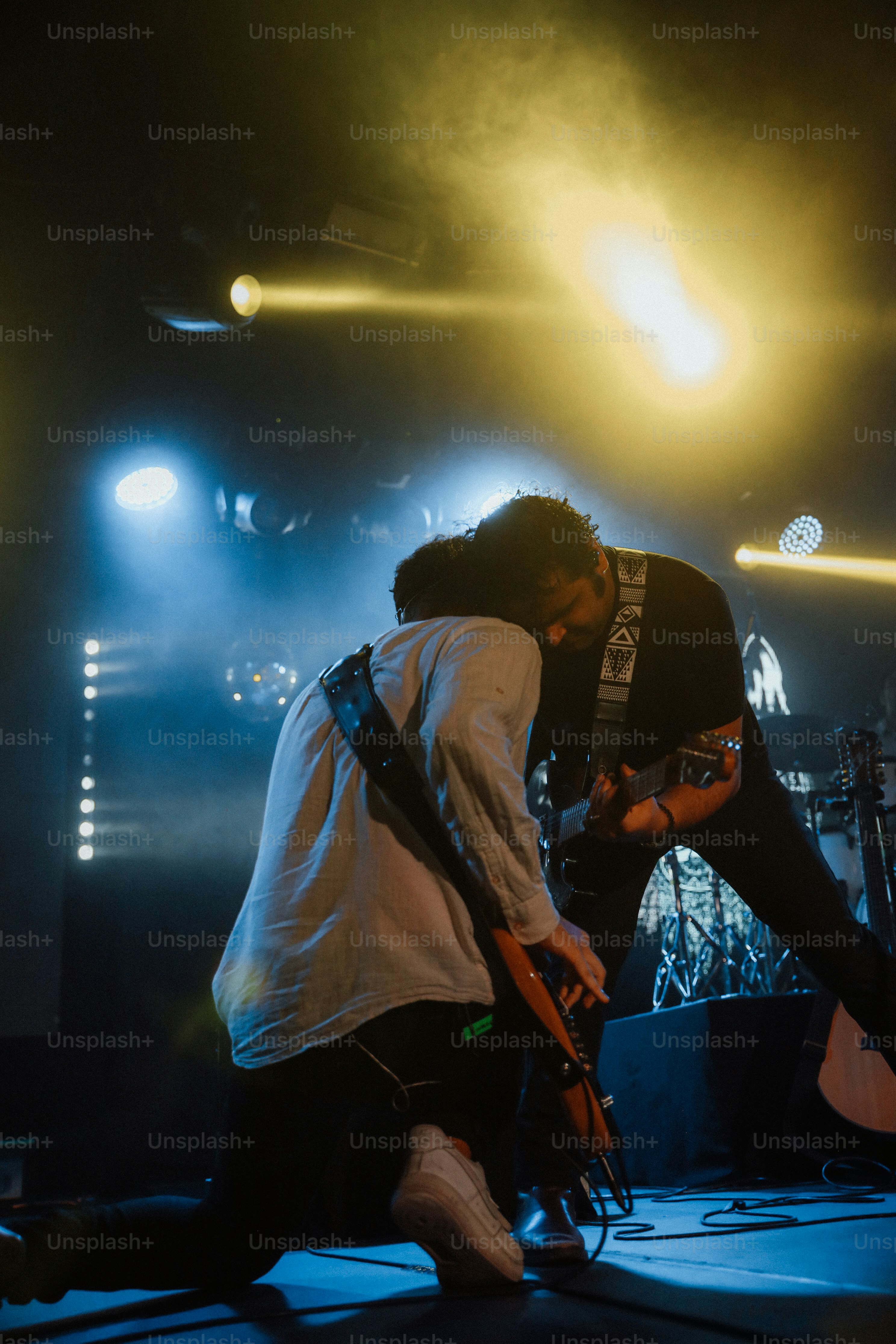 two men standing on a stage with guitars