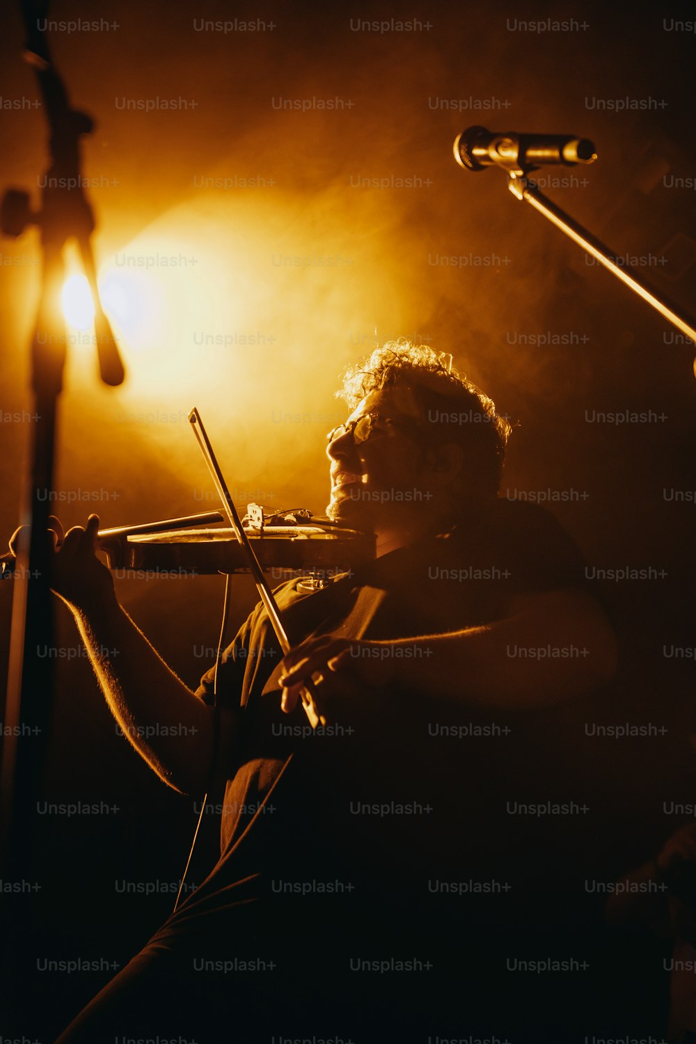 um homem tocando violino na frente de um microfone