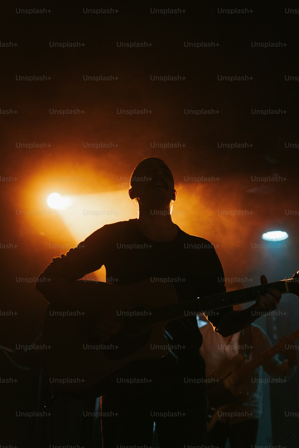 um homem segurando uma guitarra enquanto está em pé na frente de um microfone