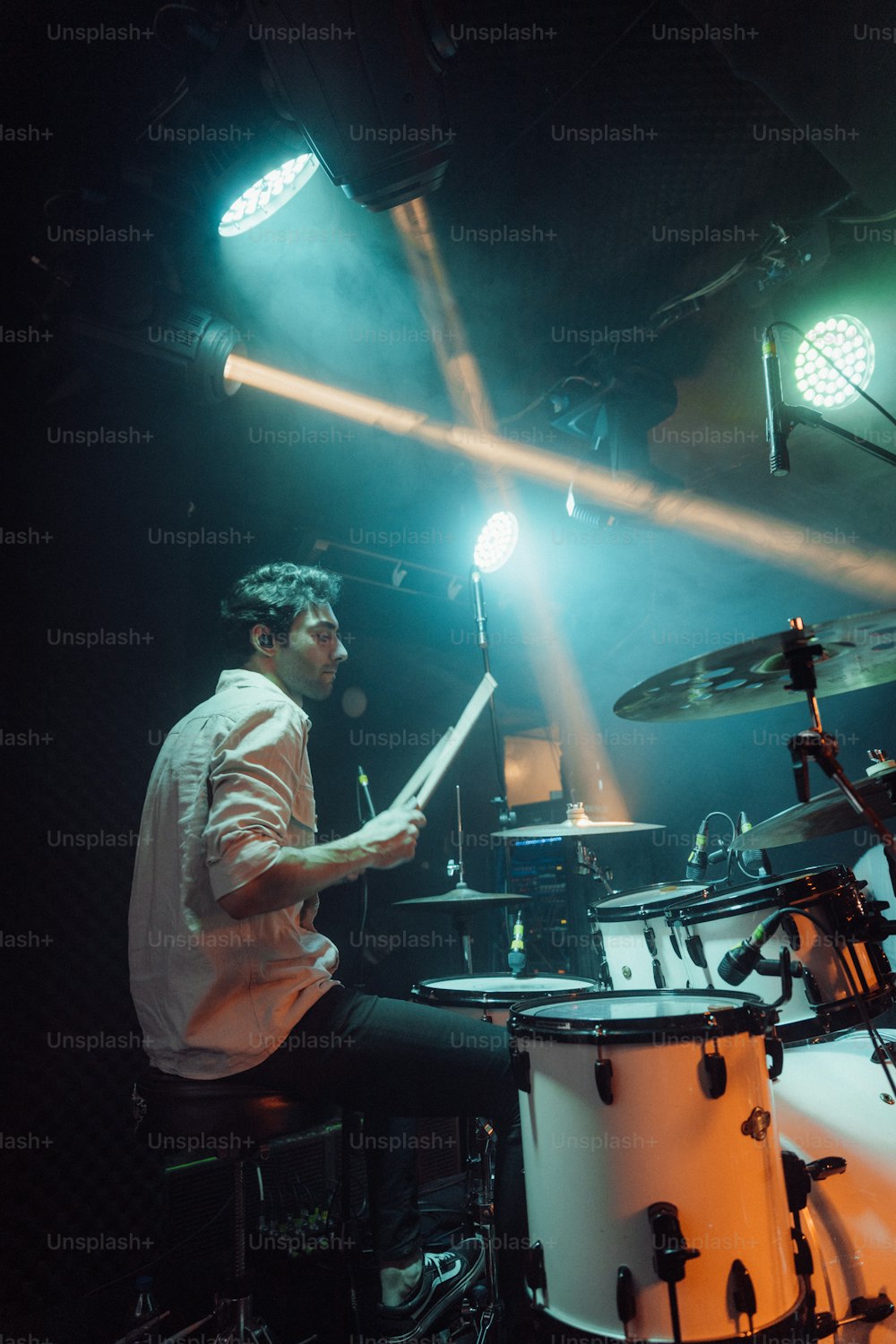 a man is playing drums in a dark room