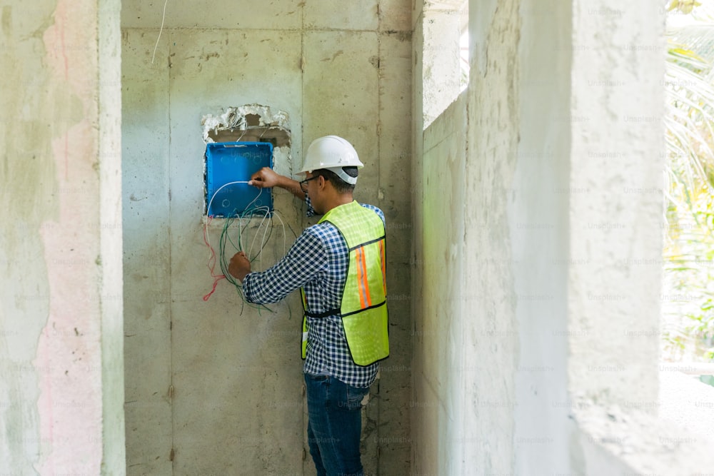 a man in a hard hat and safety vest working on a wall