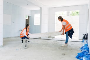 two women in orange vests moving a large piece of wood