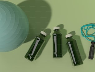 Drei Flaschen grüne Flüssigkeit neben einem blauen Ball