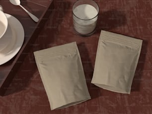 Dos bolsas de comida sentadas en una mesa junto a un vaso de agua
