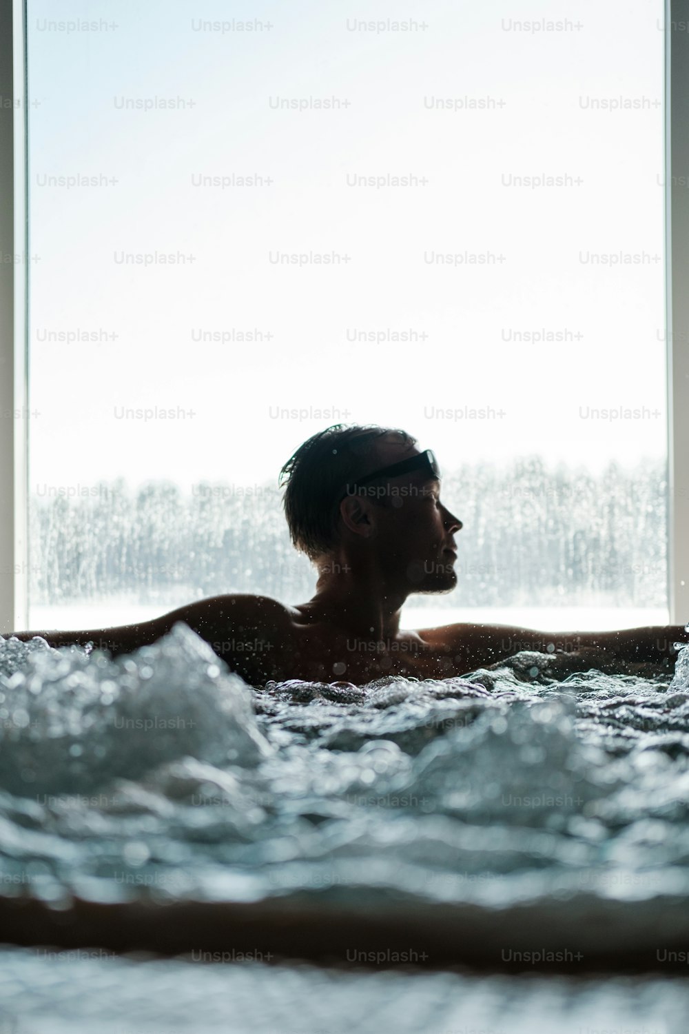 um homem sentado em uma banheira de hidromassagem na frente de uma janela