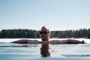 a man wearing sunglasses floating in a lake