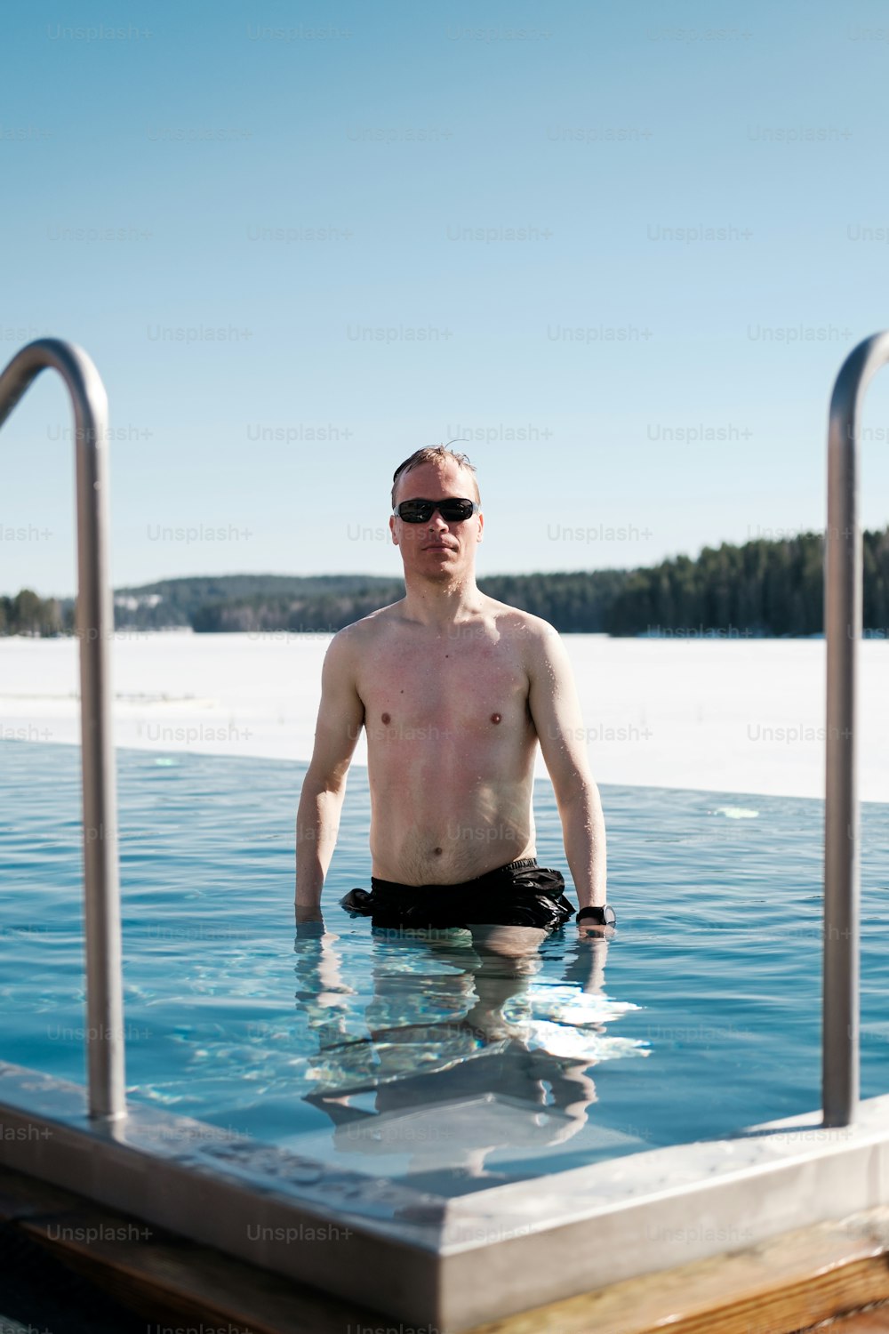 Un uomo in piedi in una piscina senza maglietta