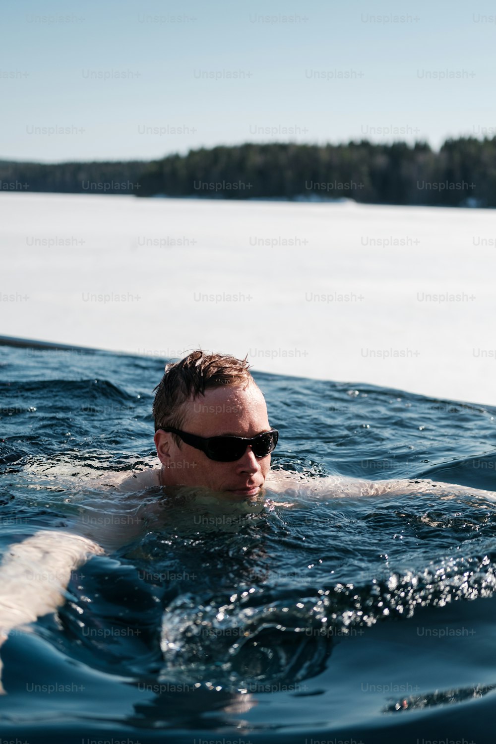 a man swimming in the water with a pair of sunglasses on