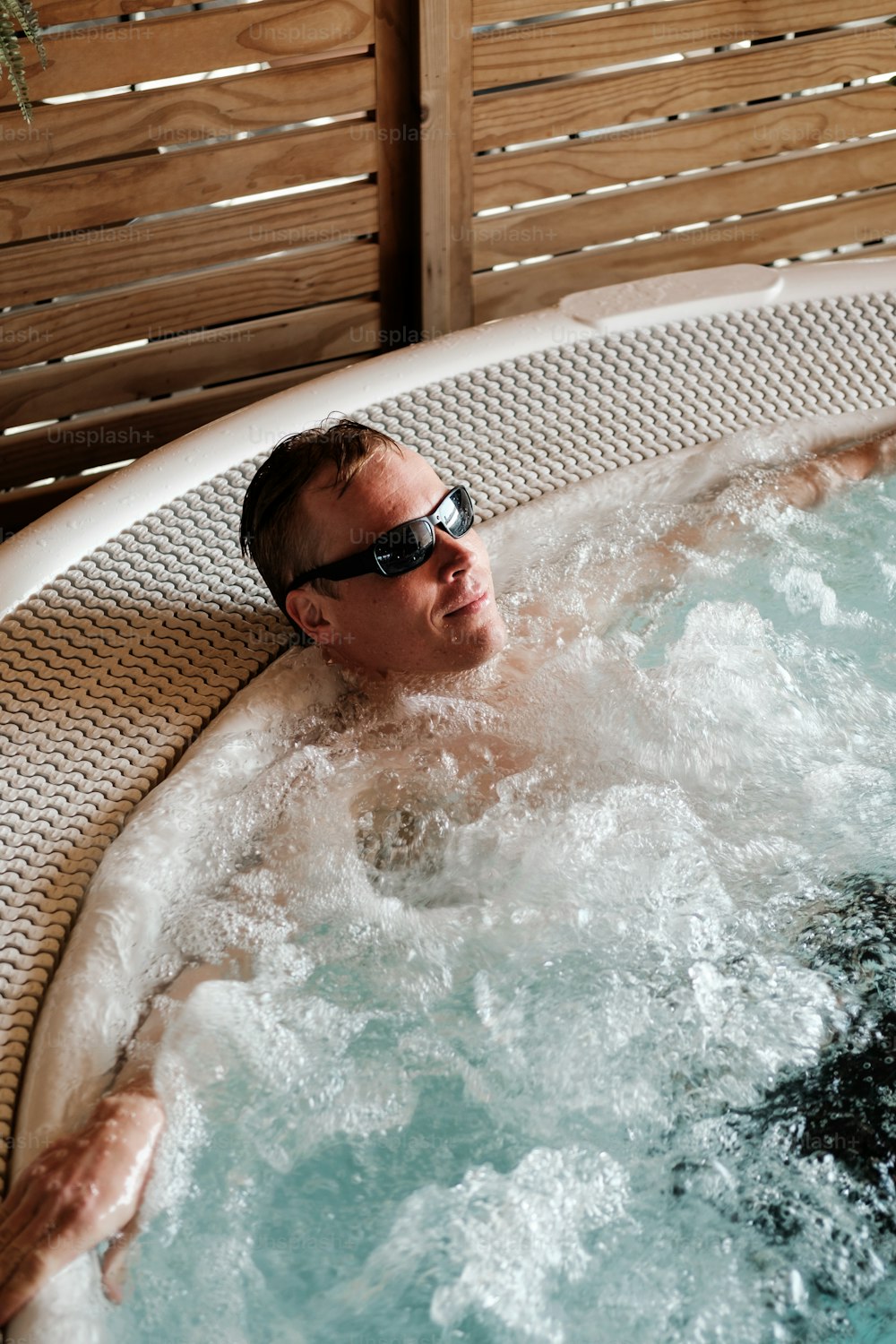 Un hombre en una bañera de hidromasaje con gafas de sol