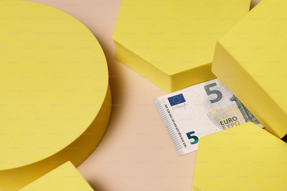 a five euro note sticking out of a hole in a yellow piece of paper