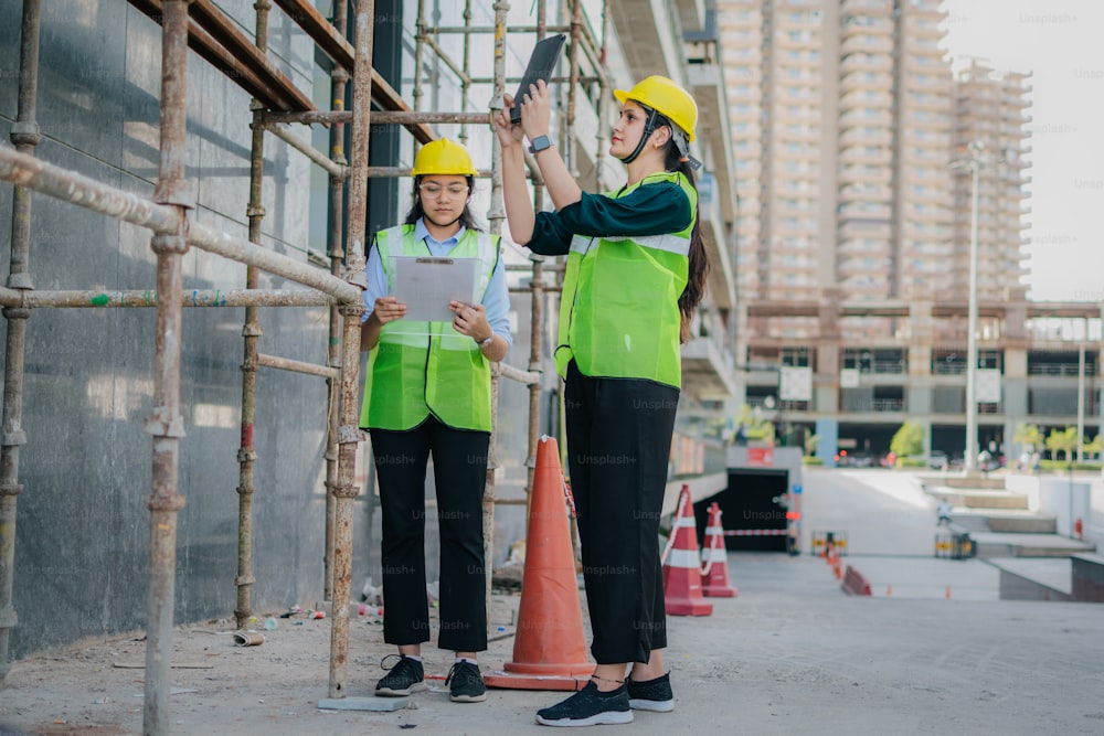 deux femmes en gilet de sécurité debout sur un chantier de construction