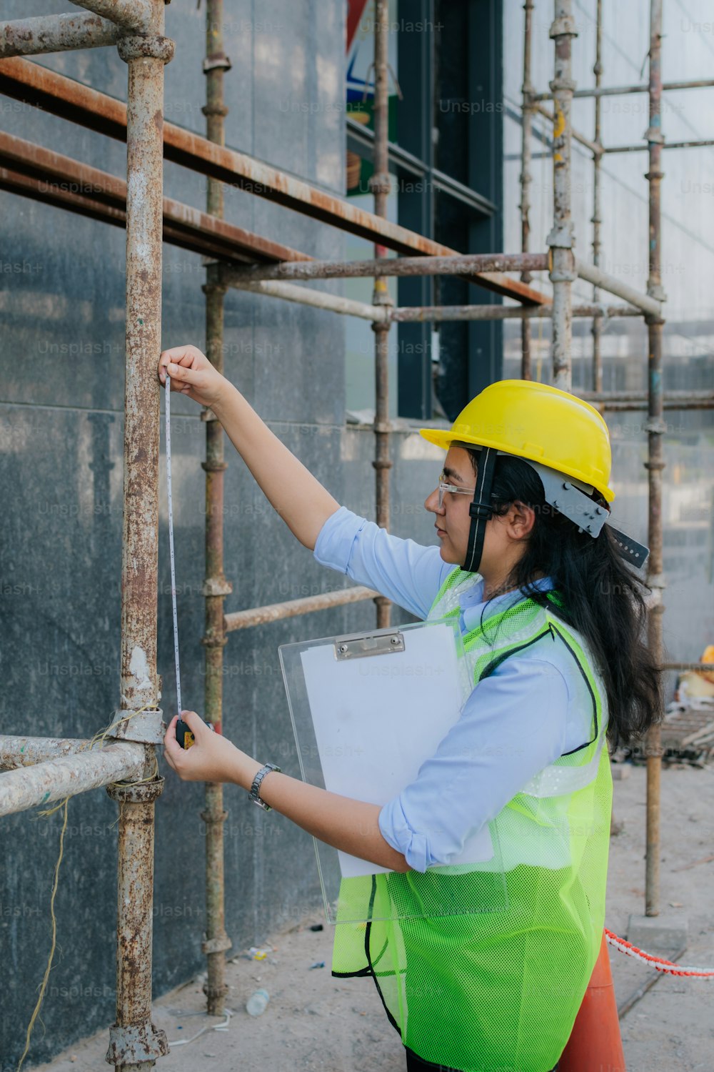 a woman in a hard hat and safety vest holding a clipboard