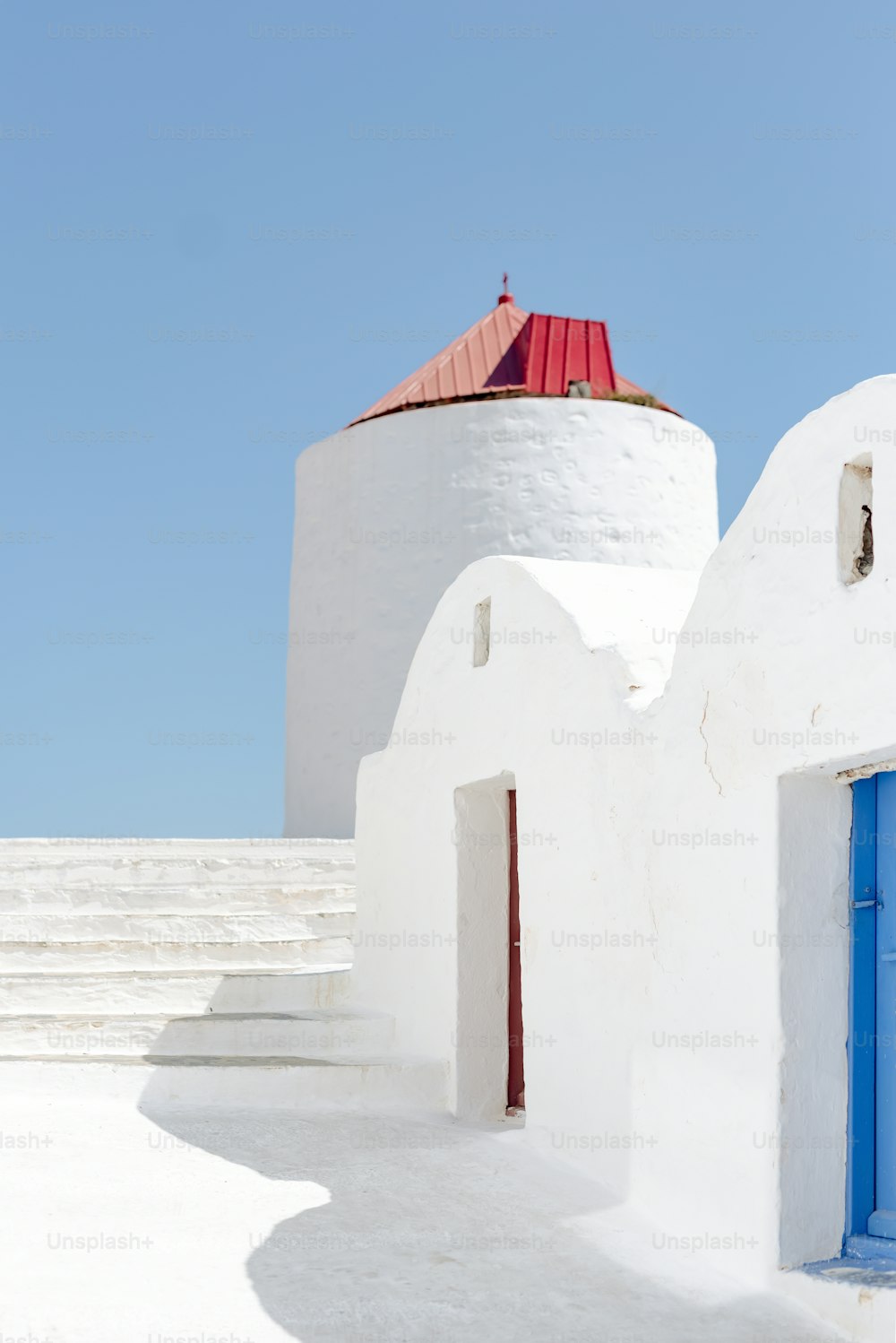 a white building with a blue door and a red roof