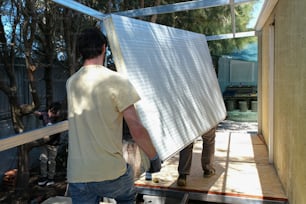 a man unloading a sheet of metal from a trailer