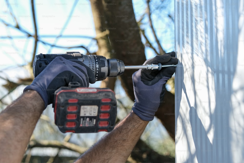 a man is holding a drill and a tool