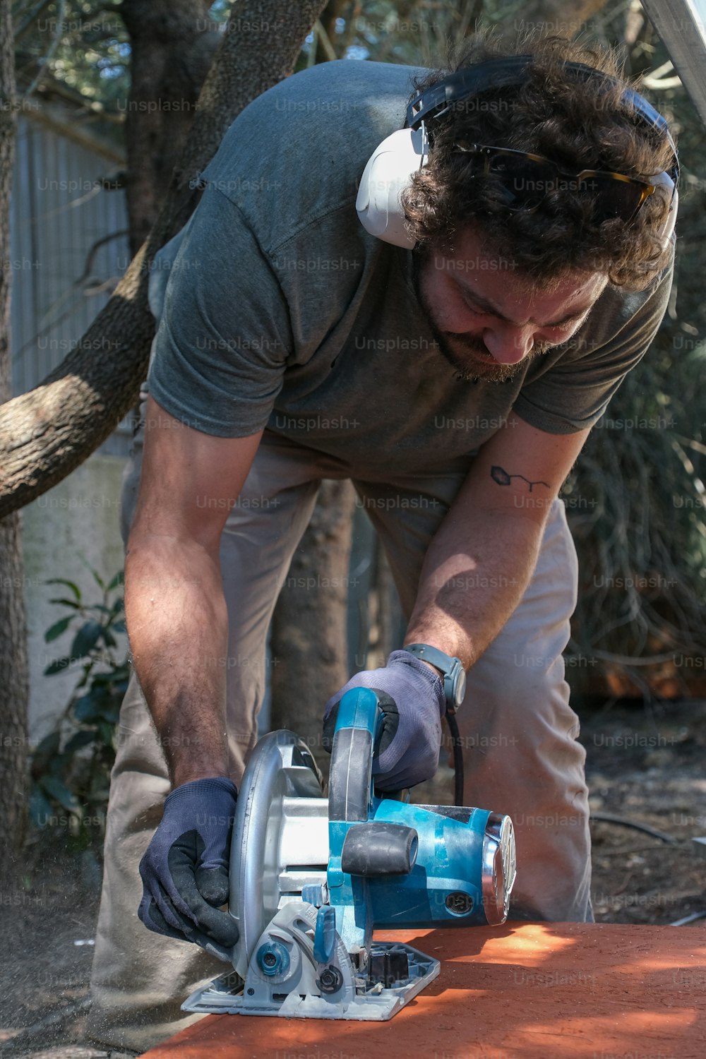 a man using a circular saw to cut a piece of wood