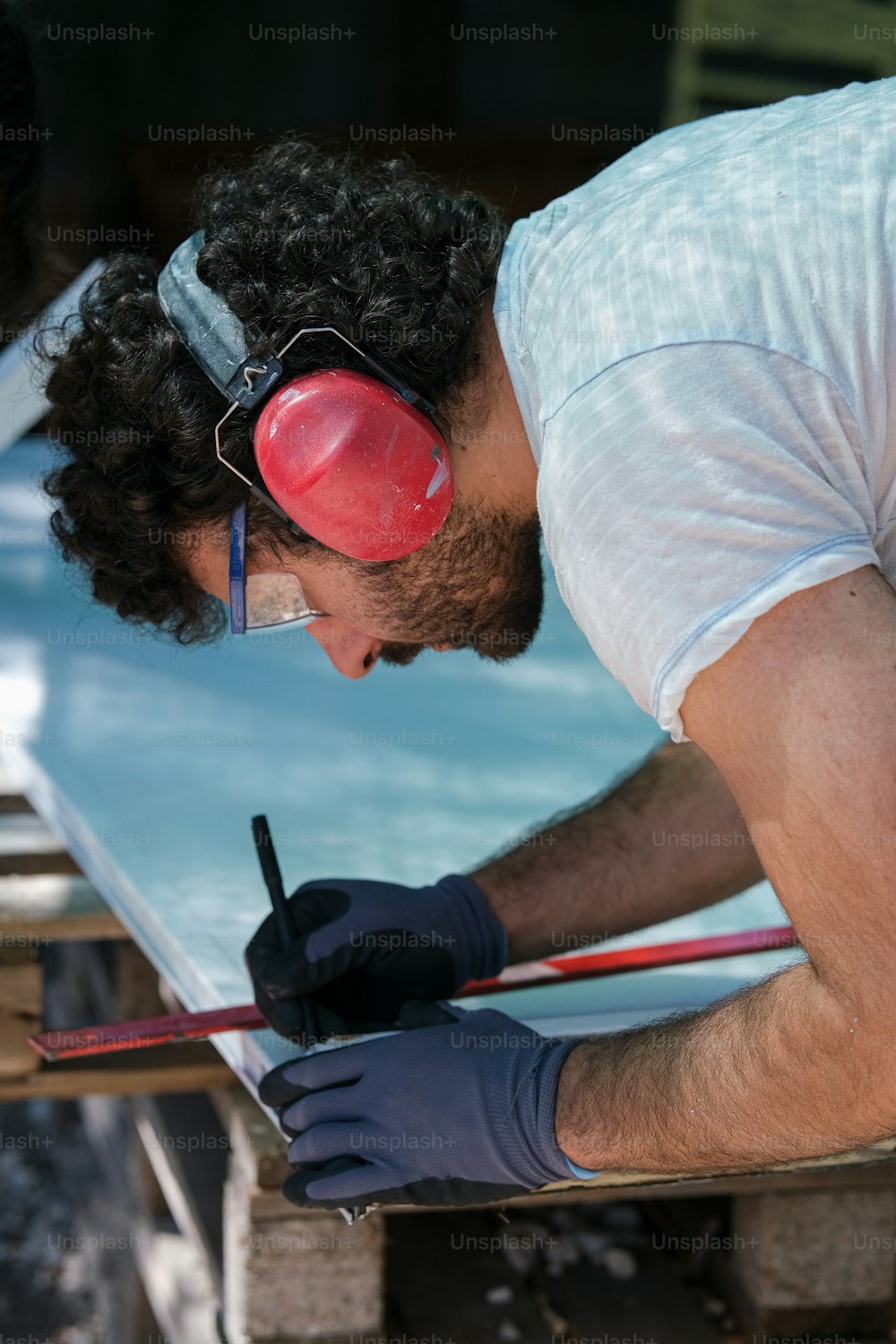 a man in a white shirt and blue gloves working on a piece of metal