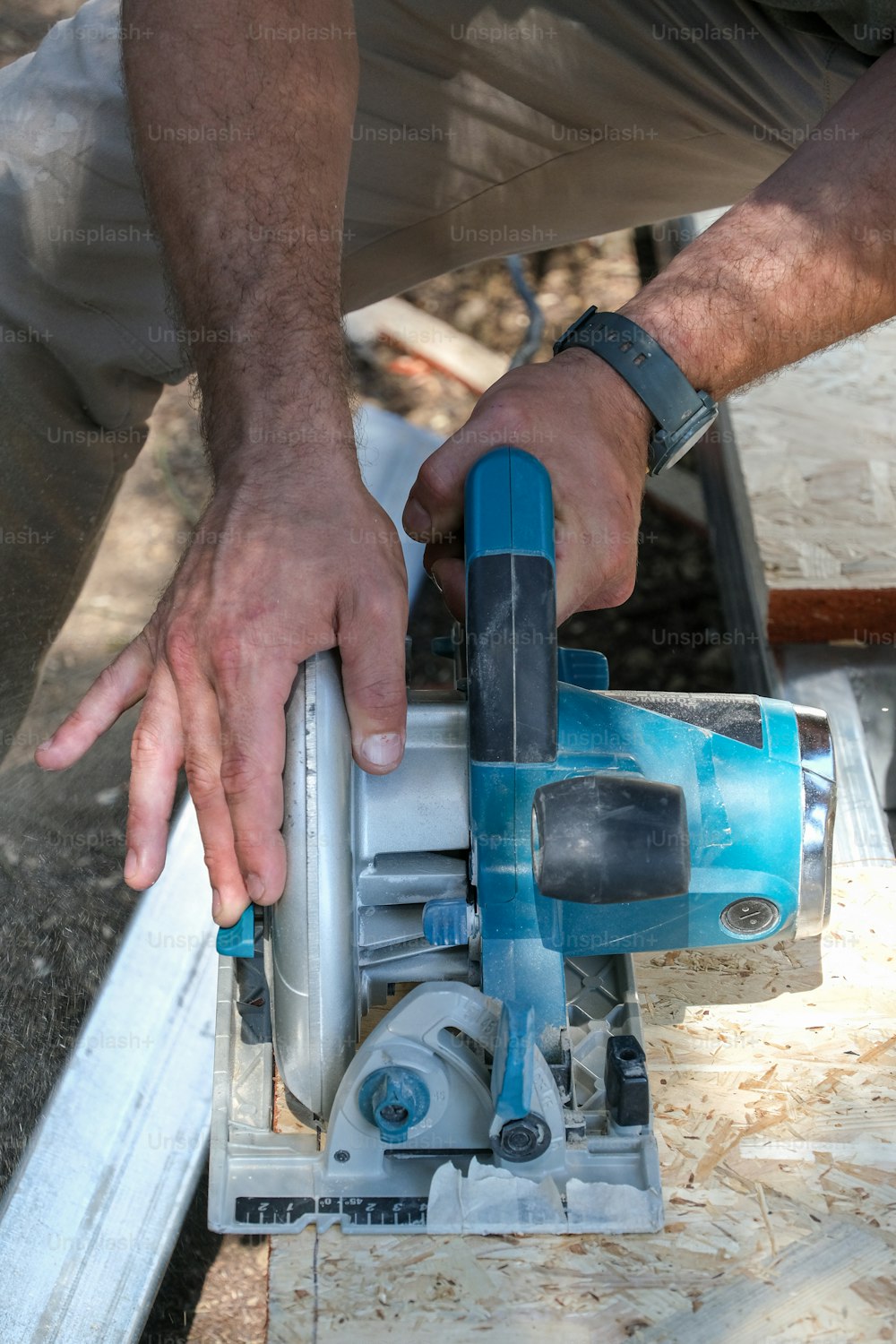 Un hombre usando una sierra circular para cortar un trozo de madera