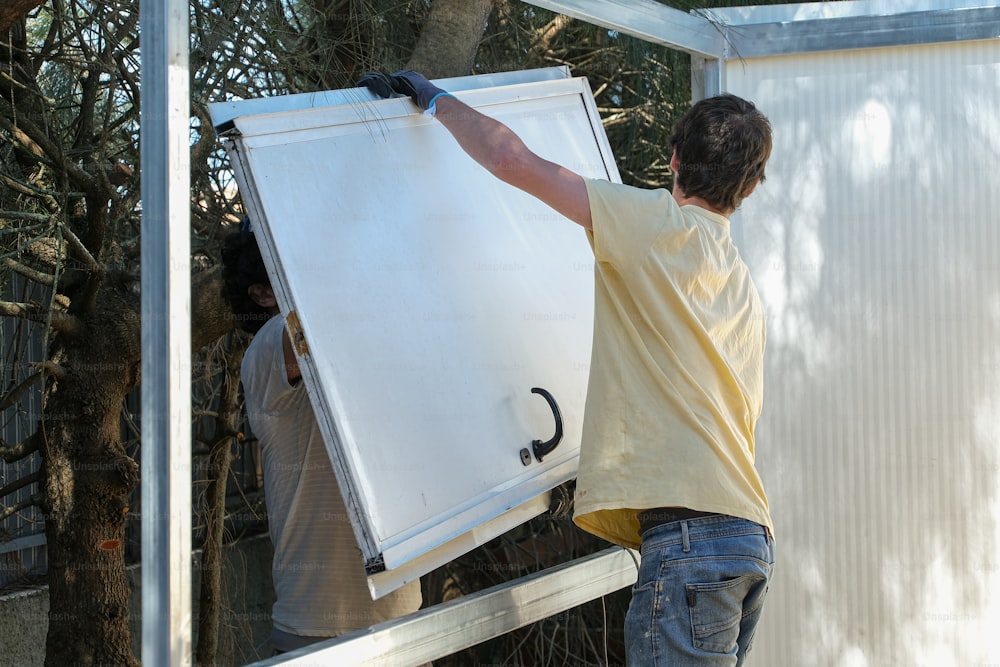 a man holding a large white board on top of a metal frame