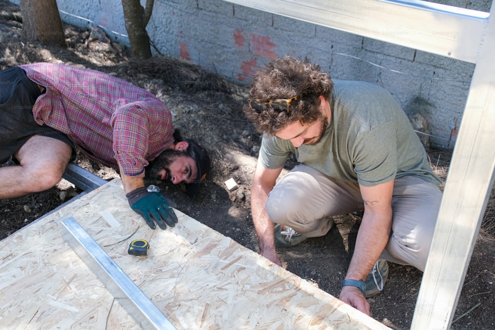 a couple of men working on a piece of wood