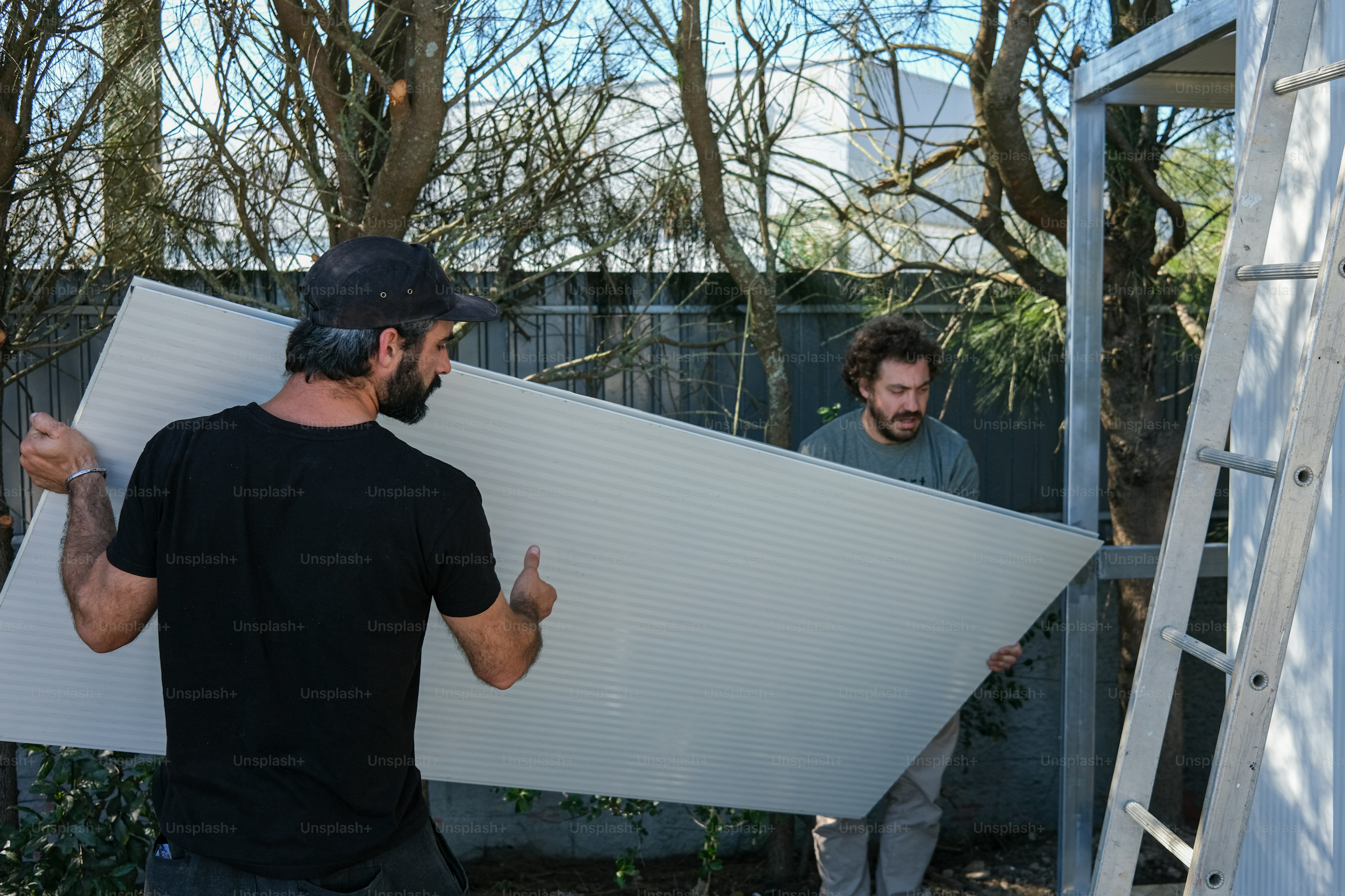 um homem segurando um grande quadro branco ao lado de outro homem