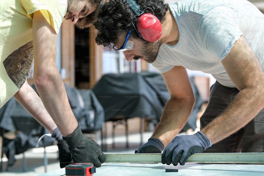 a couple of men working on a piece of wood