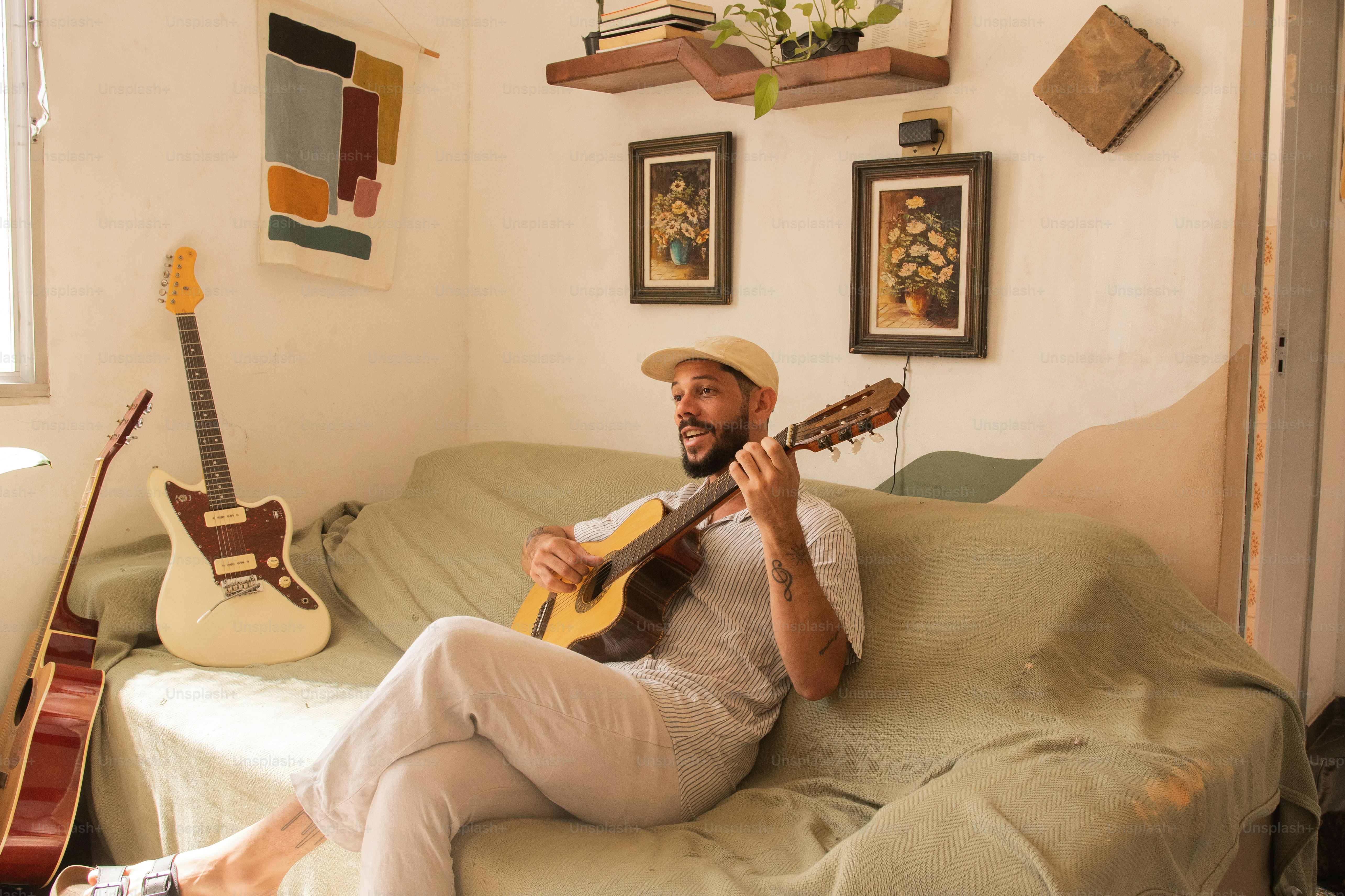 A man sitting on a couch playing a guitar photo – Jazz Image on Unsplash