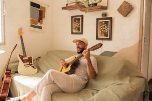 a man sitting on a couch playing a guitar