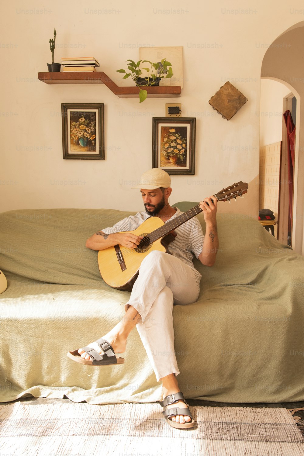 Un hombre sentado en una cama tocando una guitarra