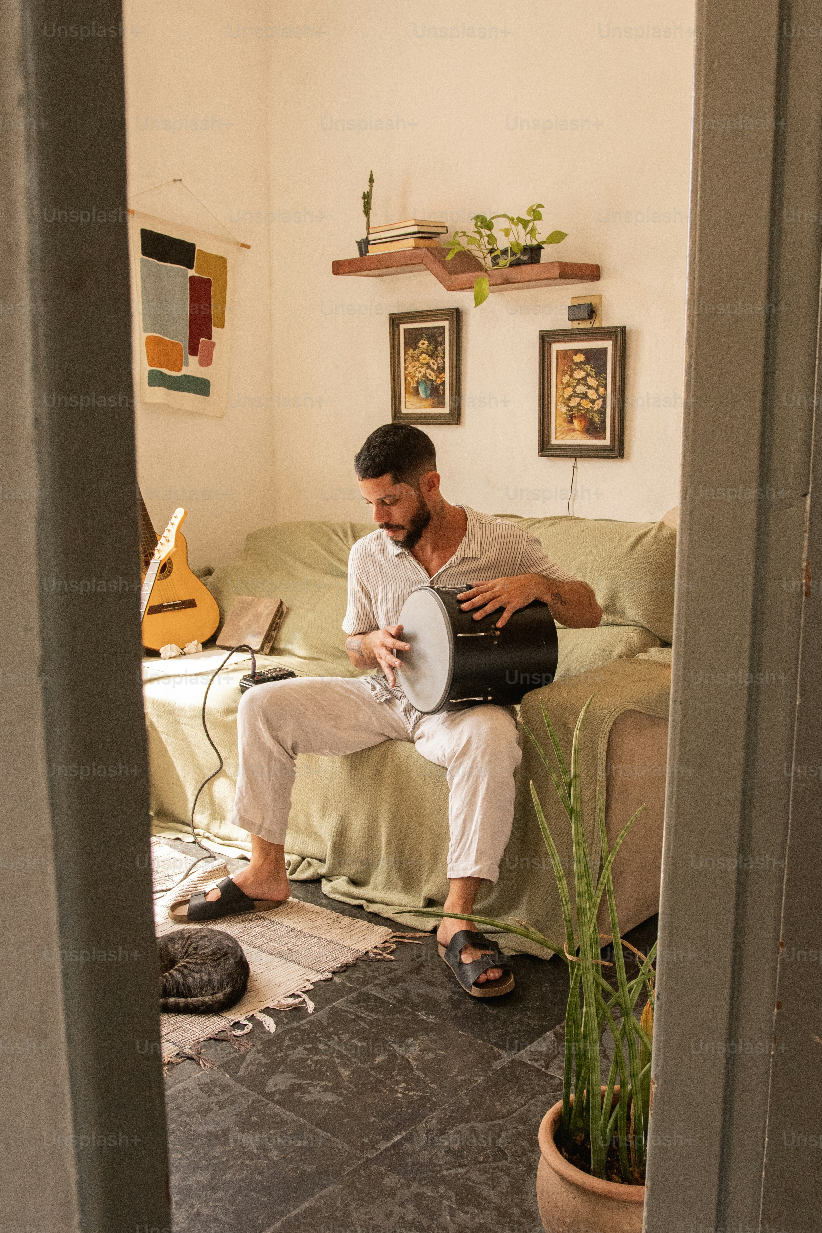 Ein Mann, der auf einer Couch sitzt und Gitarre spielt