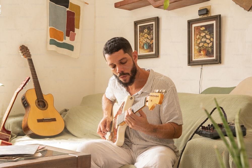 소파에 앉아 기타를 연주하는 남자