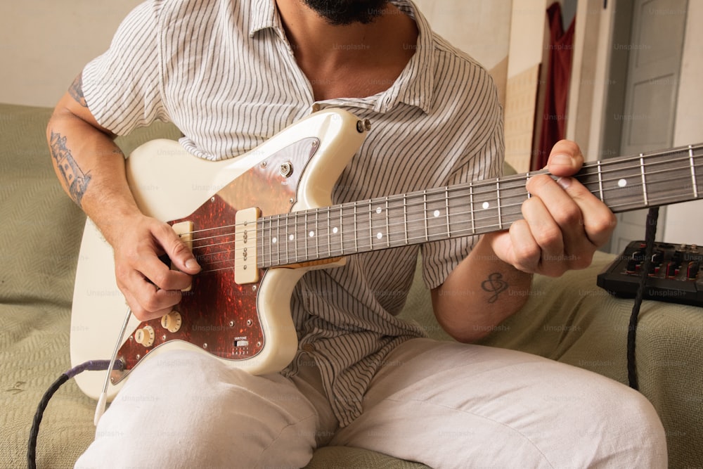 a man sitting on a couch playing a guitar