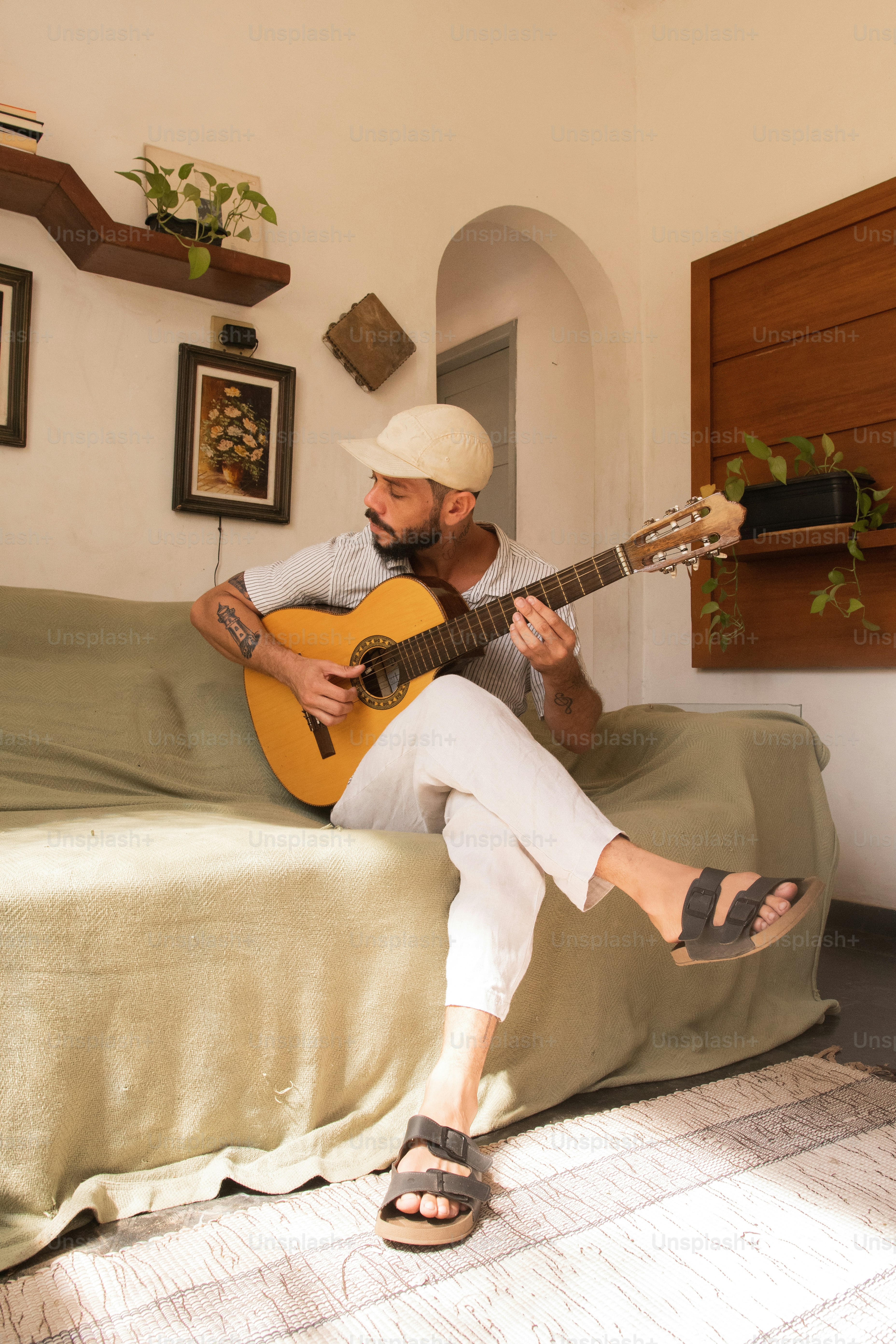 Ein Mann, der auf einem Bett sitzt und Gitarre spielt