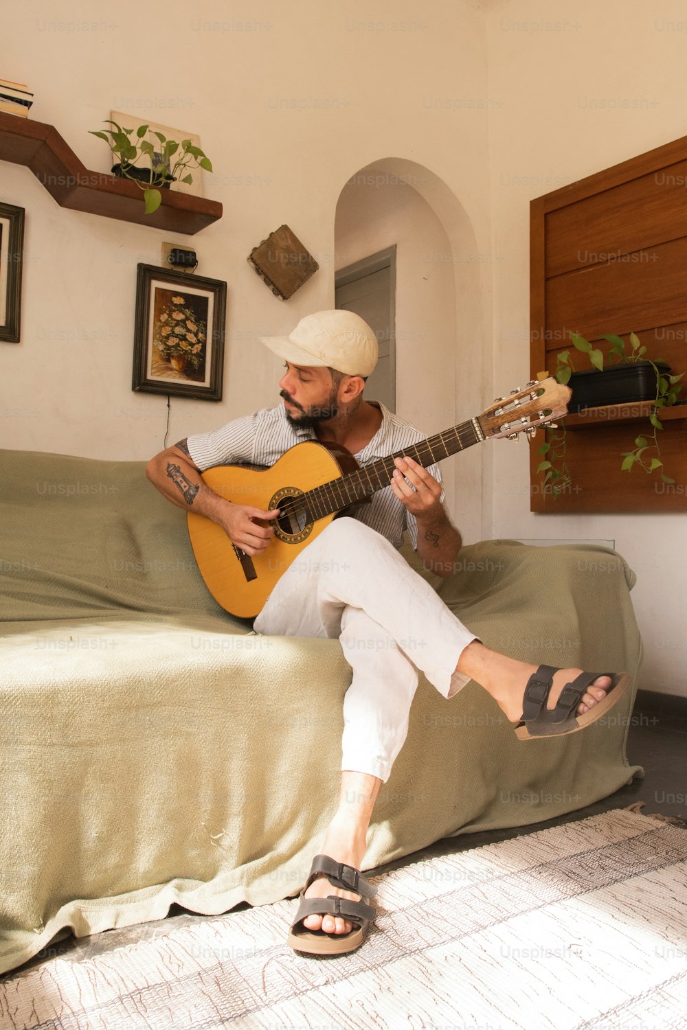 Ein Mann, der auf einem Bett sitzt und Gitarre spielt