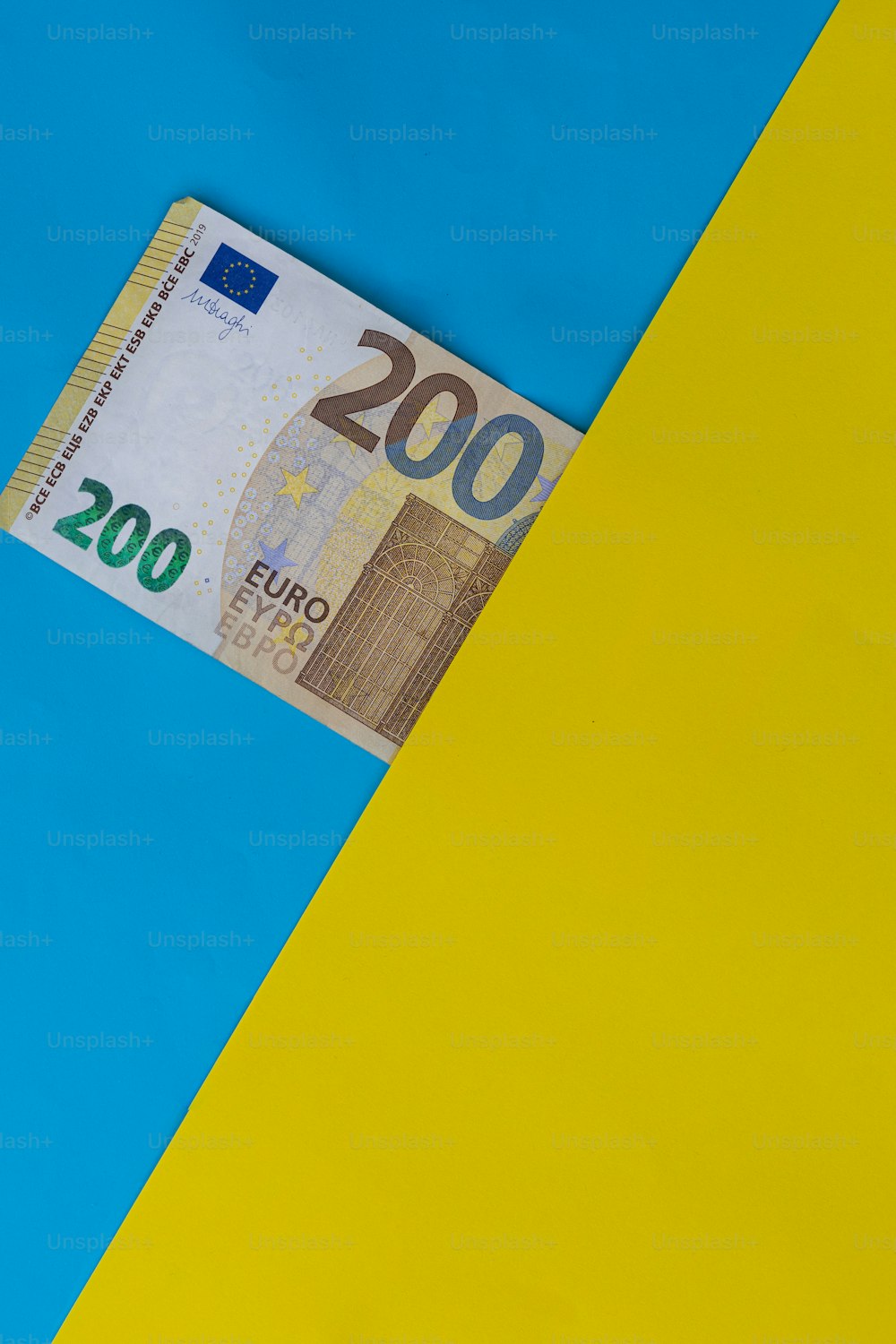 黄色と青の背景から突き出た100ユーロ札