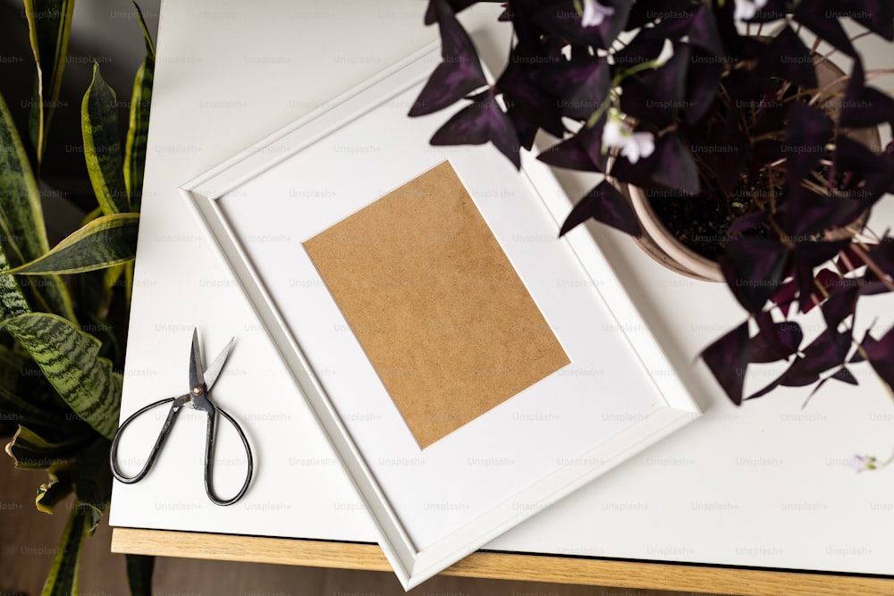un cadre photo avec un morceau de papier brun à côté d’une paire de ciseaux
