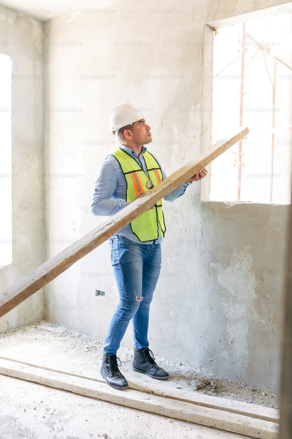 Un hombre con casco y chaleco de seguridad parado en una habitación en construcción