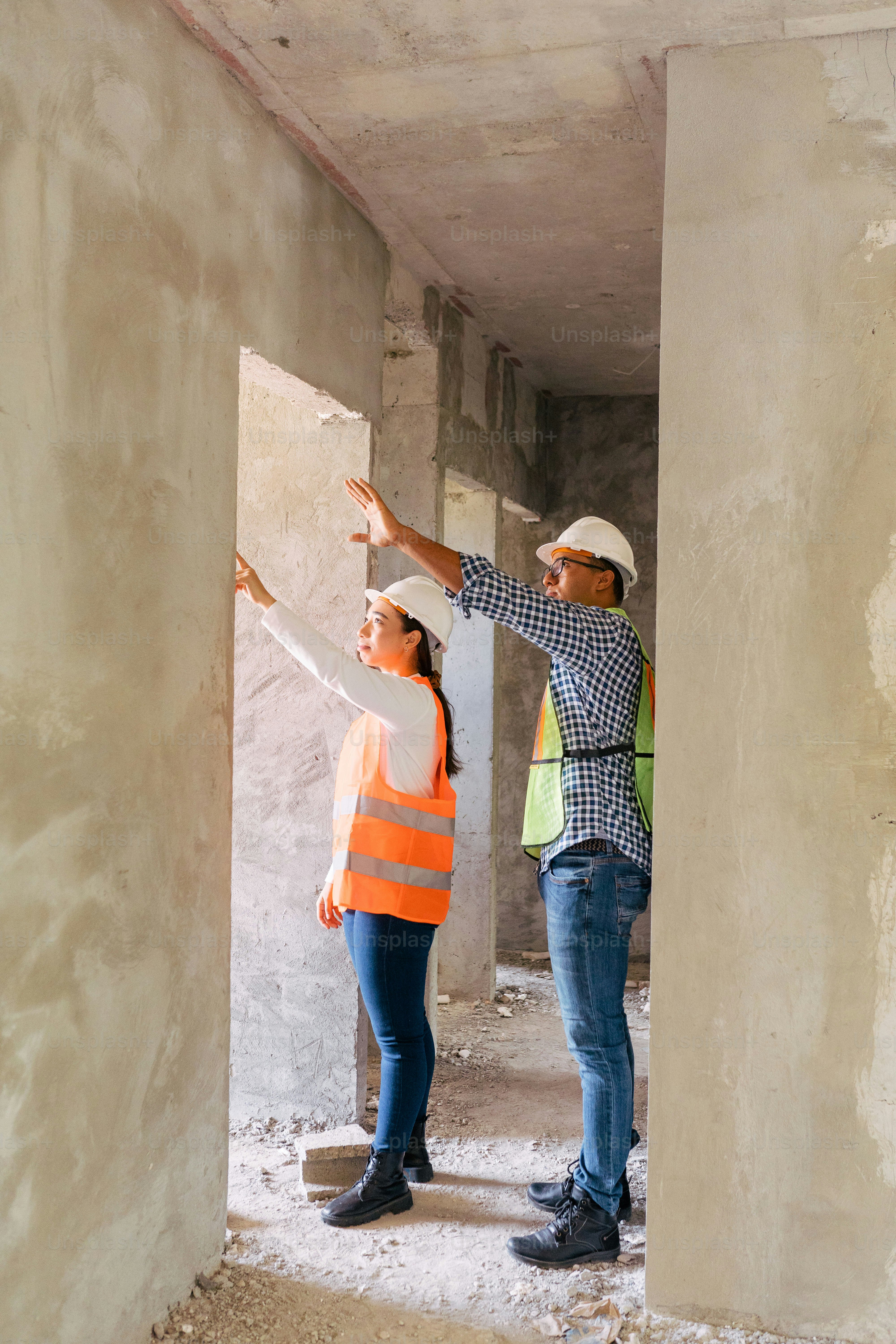 A couple of people that are standing in a building photo – Construction ...