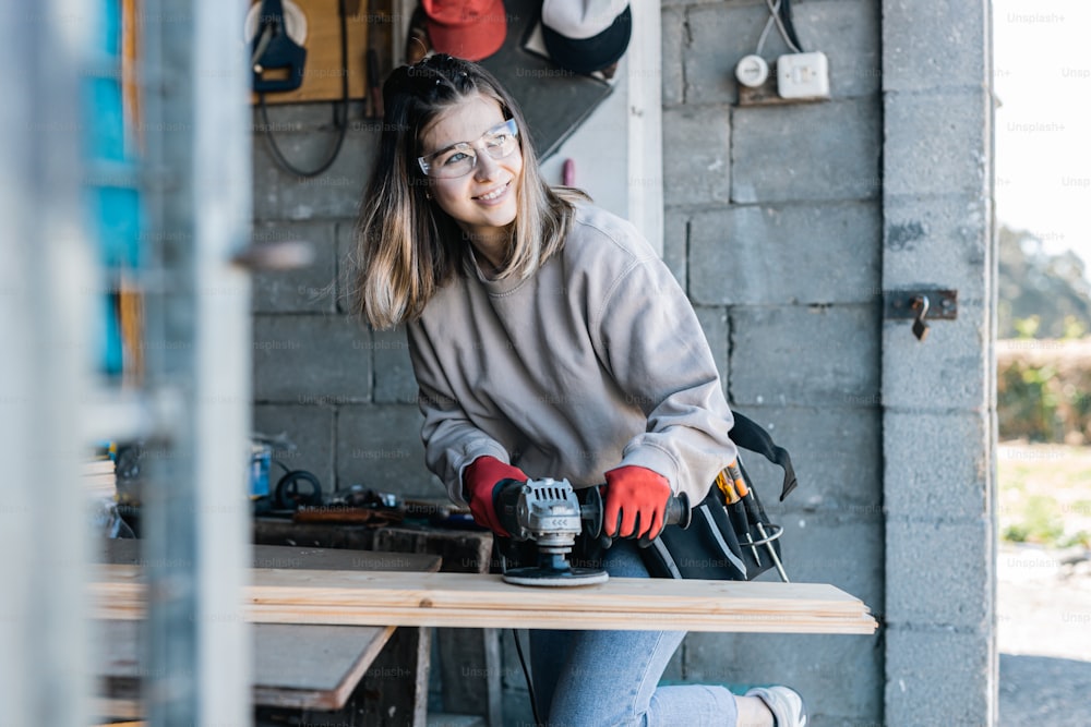 a woman in a gray sweater and red gloves sanding a table