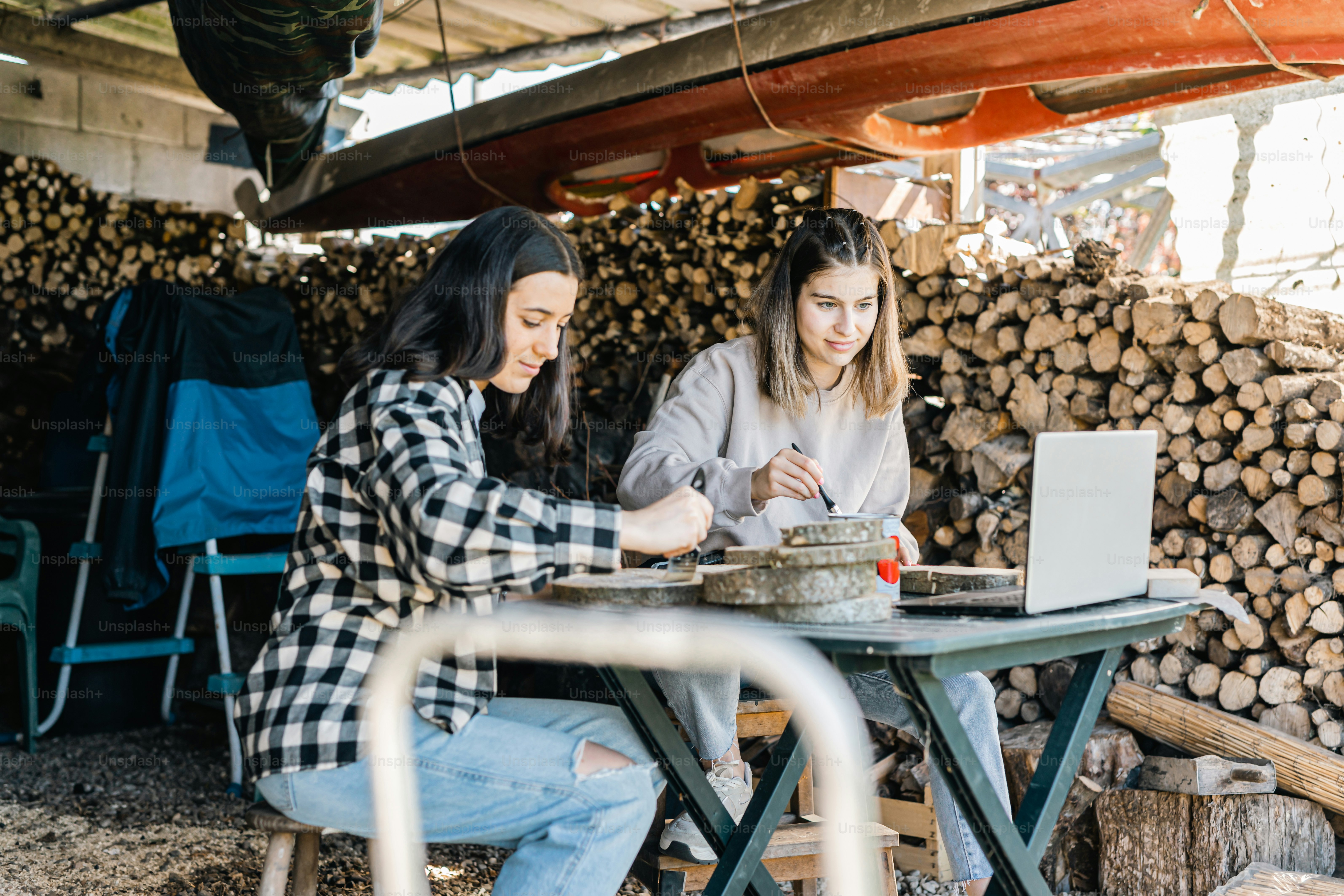 two women sitting at a table with a laptop