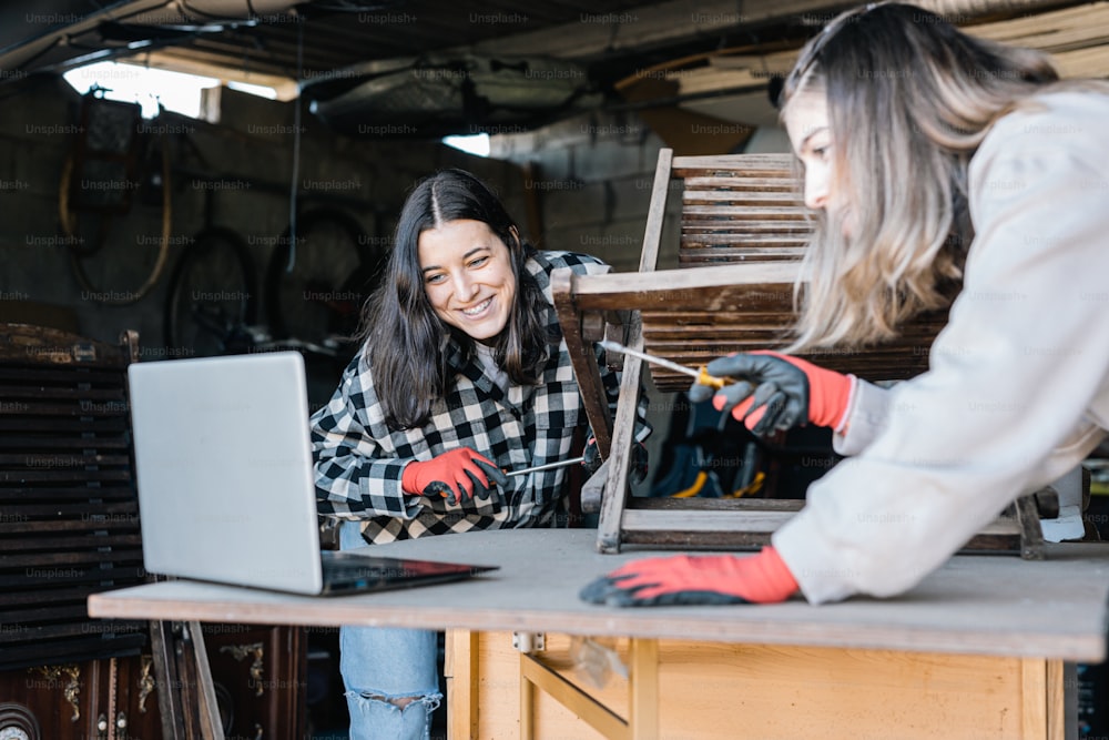 two women working on a laptop in a garage