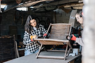 two women working on a wooden chair in a shop