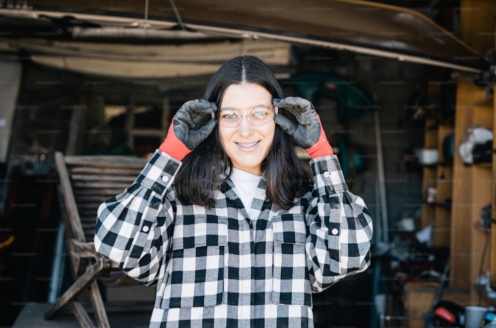 a woman in a black and white checkered shirt holding her hands up to her