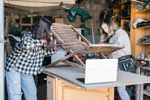 duas mulheres que trabalham em uma cadeira de madeira em uma loja