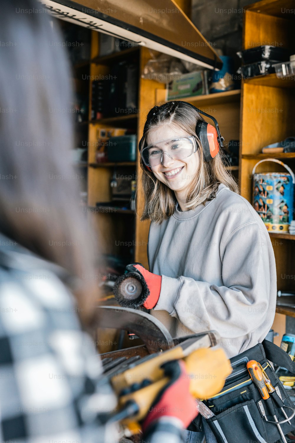 a woman wearing headphones and holding a circular saw